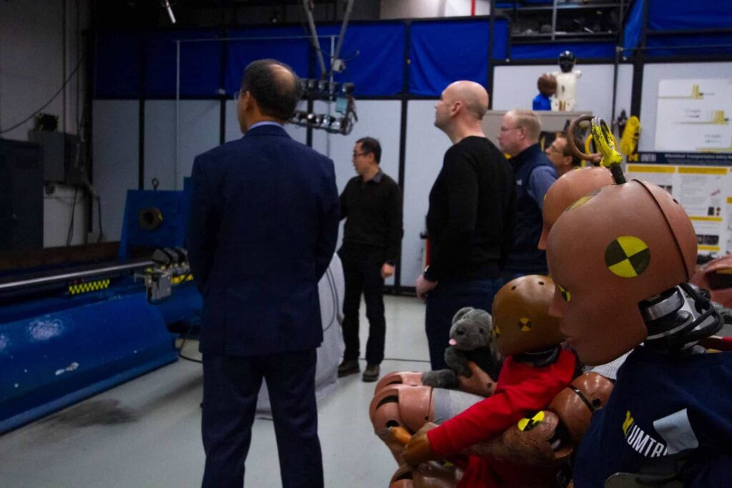 A crash test dummy sits in the foreground as Dr. Henry Liu and Jingwen Hu speak with Jonathan Morrison