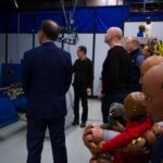 A crash test dummy sits in the foreground as Dr. Henry Liu and Jingwen Hu speak with Jonathan Morrison