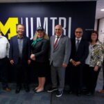 Eric Wingfield, Henry Liu, Seval Oz, Firas Ibrahim, Hamid Ghasemi, Debby Bezzina, and Greg McGuire standing in front of the UMTRI sign